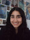 Person with long dark hair smiling in front of a wall with posters.